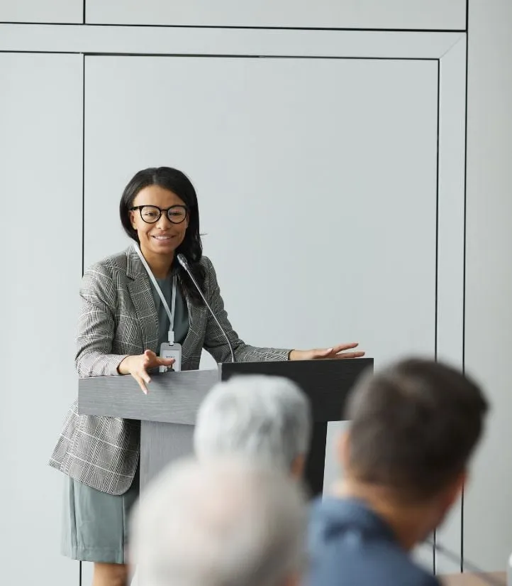 A presenter speaking at a podium in front of an audience